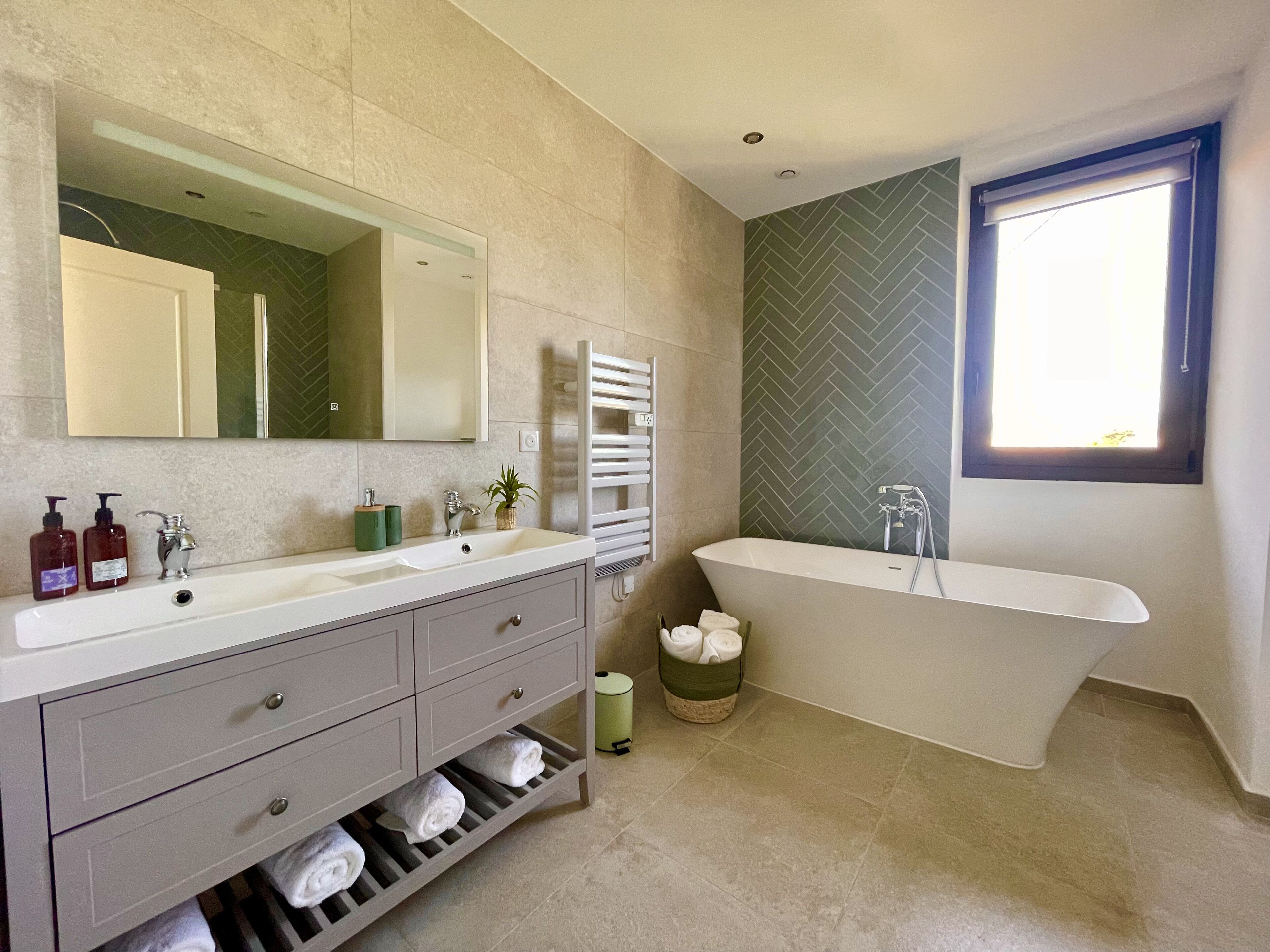 Une salle de bain moderne avec un grand meuble-lavabo, une baignoire sur pieds et un grand miroir.