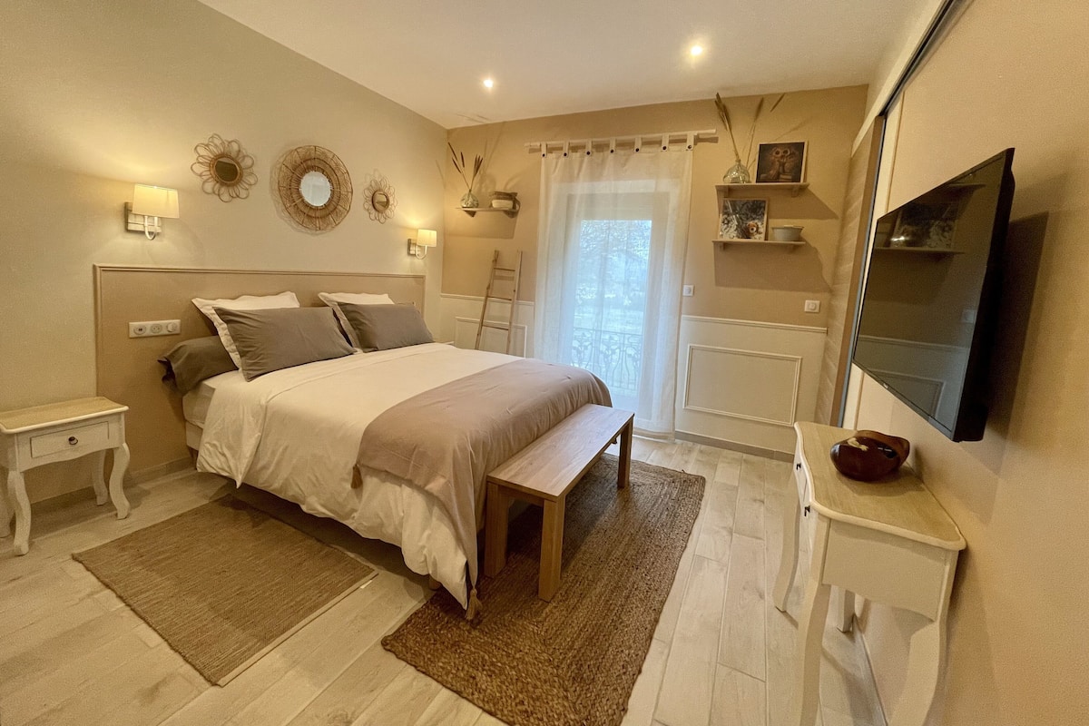 A bedroom with a bed, bedside tables, a bench, a TV, and a window with curtains.