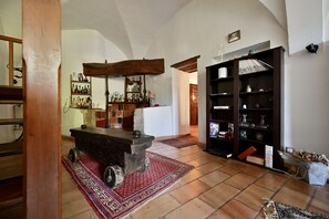 A rustic interior with a stone cart, shelves with bottles, and a red rug. - Bastide Beaudinard (Aubagne)