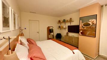 A bedroom with a bed, a dresser, a chair, a television, and shelves with decorative items.