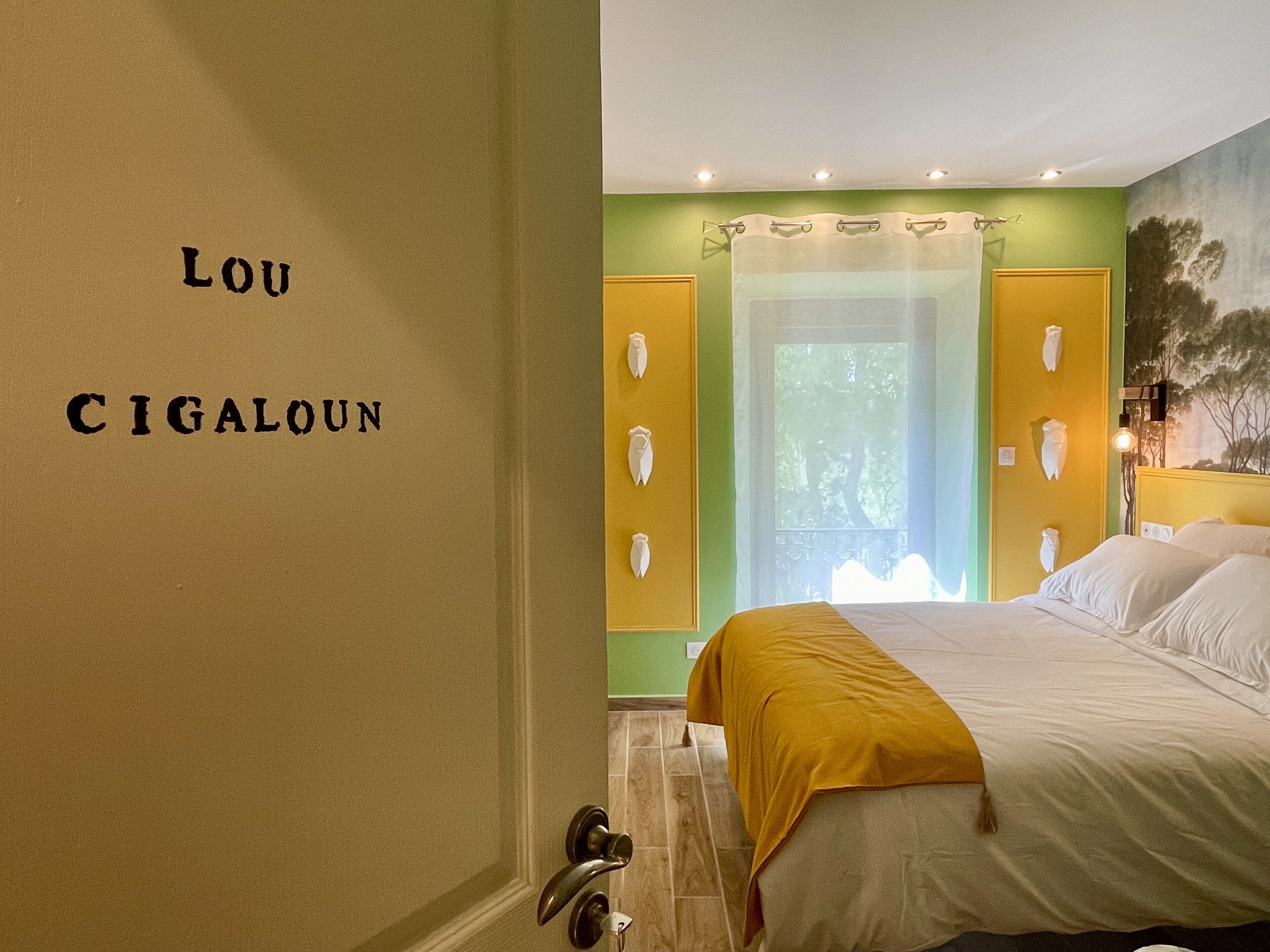 A hotel room with a bed, a yellow wall, and a green door.