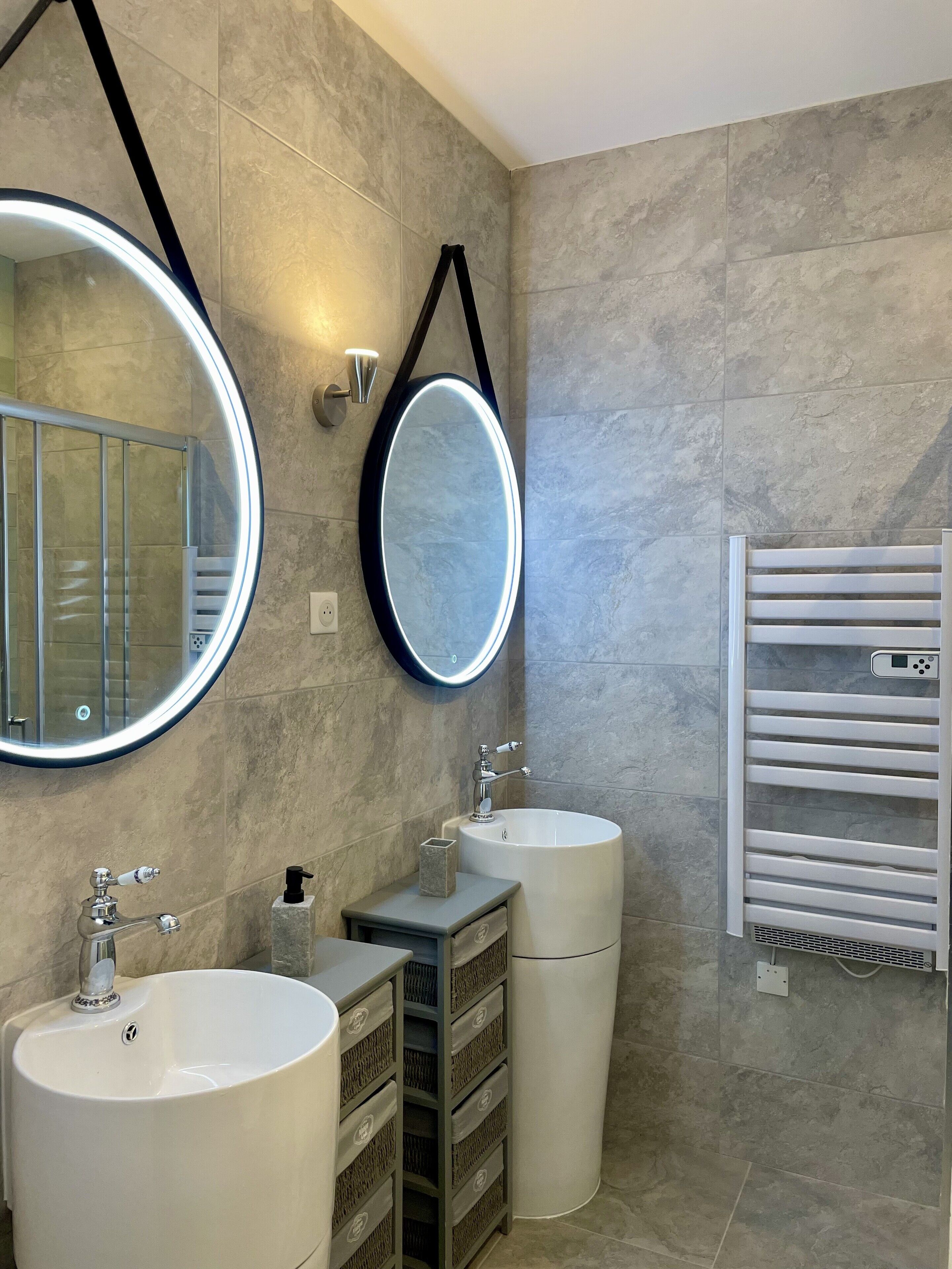 Une salle de bain moderne avec deux lavabos, un grand miroir et un porte-serviettes.