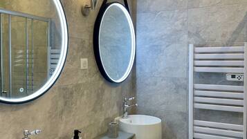 Une salle de bain moderne avec deux lavabos, un grand miroir et un porte-serviettes.