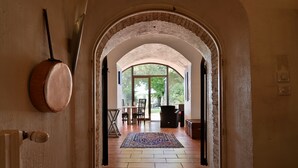 Un arco de entrada da a un comedor con un tapete estampado, una mesa, sillas y vistas al exterior con vegetación.