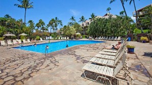 A pool area with lounge chairs, palm trees, and a clear blue sky. - Casual Kihei! WiFi, AC, Ceiling Fans, Laundry, Kitchen, Lanai, TV–Kamaole Sands 8209 (KIHEI)