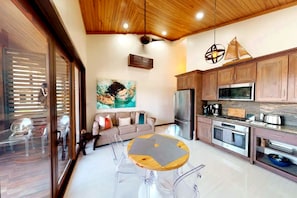 Una cocina moderna con armarios de madera, un refrigerador de acero inoxidable y una zona de comedor con una mesa redonda y sillas.