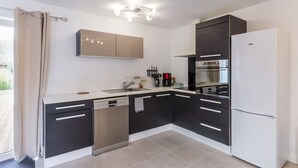 Una cocina moderna con muebles negros y blancos, lavavajillas, refrigerador y horno empotrado.