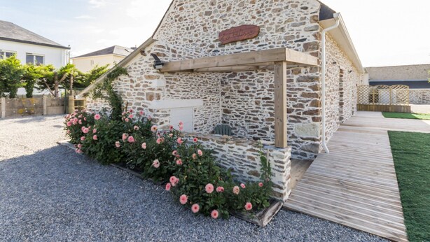 Un edificio de piedra con una terraza de madera y un letrero que dice "La maison".
