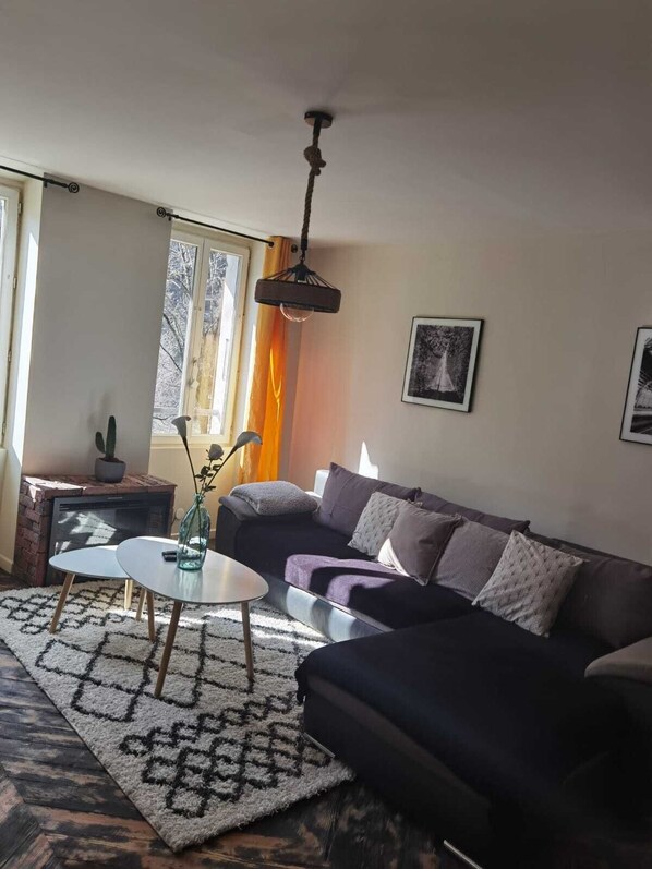 Un salon avec un canapé, une table basse, une cheminée et une fenêtre avec des rideaux.