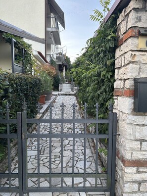 A gated entrance with a stone pathway leading to a building with a stone facade and a metal gate. - Premium apartment Sunny (Porec)