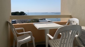 A balcony with a white table and two white chairs, overlooking a body of water and a parking area. - 2* Apt with AC and Pets Allowed in Balaruc-les-Bains (Balaruc-les-Bains)