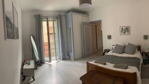 Un dormitorio con cama, mesitas de noche, un espejo y una puerta corredera que da a un balcón.