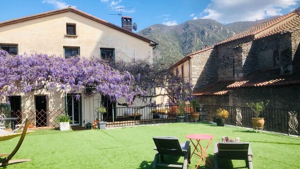 Un patio con césped, dos sillones de descanso y una mesa.