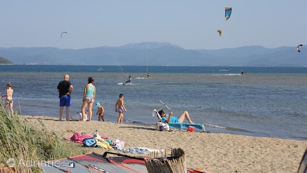 Uma praia com pessoas, pipas e barcos.