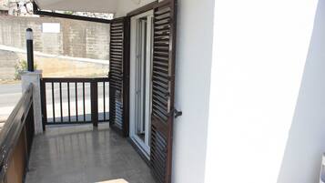 A balcony with a metal gate, a concrete wall, and a tiled floor.