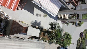 Vista de una calle con un edificio de techo rojo, una escalera y un coche aparcado.
