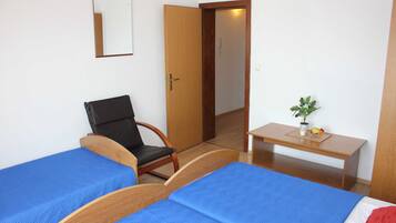 Una habitación con dos camas, una silla, un escritorio, un espejo y una planta pequeña.