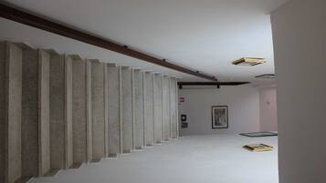 Un pasillo con pared de hormigón, vigas de madera y un cuadro enmarcado en la pared.