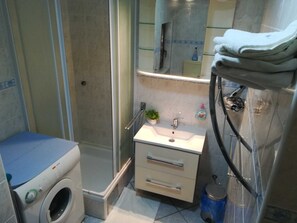 A compact bathroom with a shower, a sink, a small cabinet, and a washing machine. - Guest House San Antonio (Ploce)