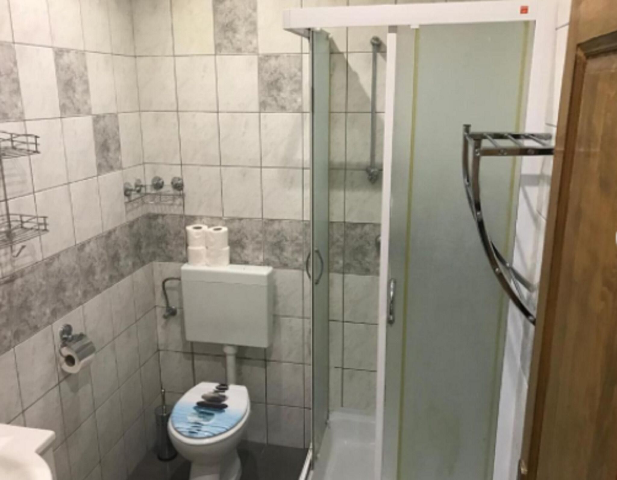 A small bathroom with a toilet, a shower, and a sink.
