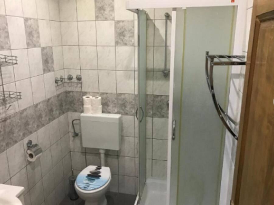 A small bathroom with a toilet, a shower, and a sink.