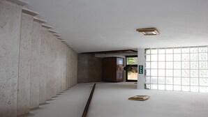 Um interior amplo com um corredor extenso, uma janela grande com padrão de grade e uma porta de madeira.
