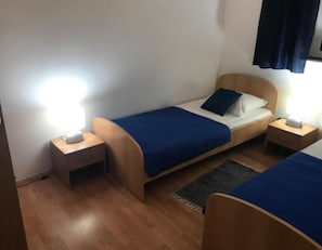 A small, neatly arranged bedroom with two single beds, wooden headboards, and bedside tables with lamps. - Guest House San Antonio (Ploce)