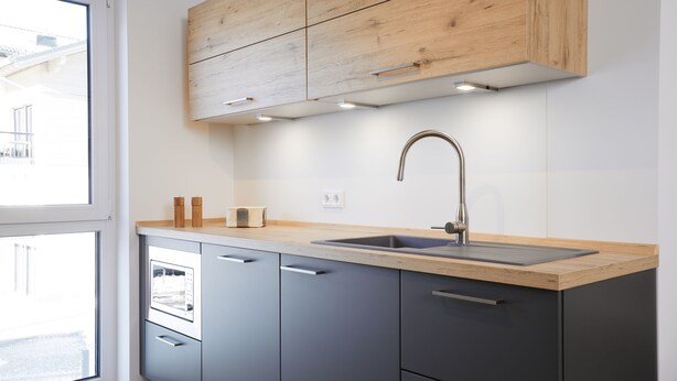 A modern kitchen with grey cabinets, a wooden countertop, and a stainless steel sink. - Newly built holiday apartment in a top location in Garmisch-Partenkirchen (Garmisch-Partenkirchen)