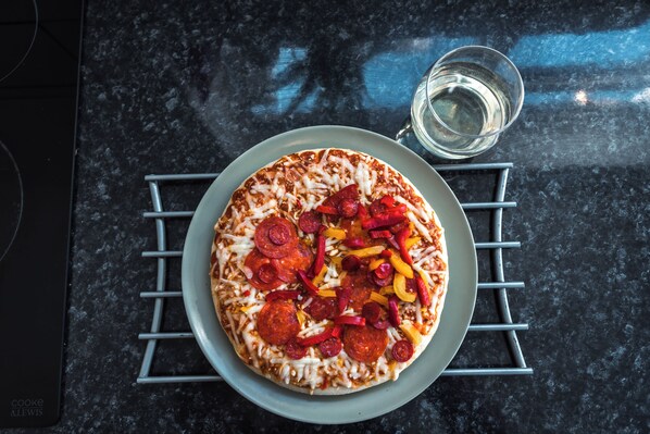 A pizza with pepperoni and bell peppers on a plate, placed on a kitchen counter. - 3 Bedrooms house ideal for long Stays! (Southampton)