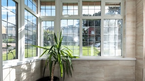 Ein Zimmer mit großem Fenster, einem Blumentopf und Blick auf eine Wohngegend.