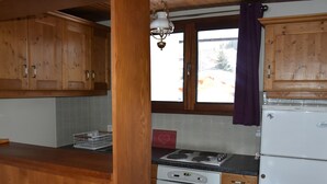 Une cuisine avec des meubles de rangement en bois, une cuisinière et un réfrigérateur.