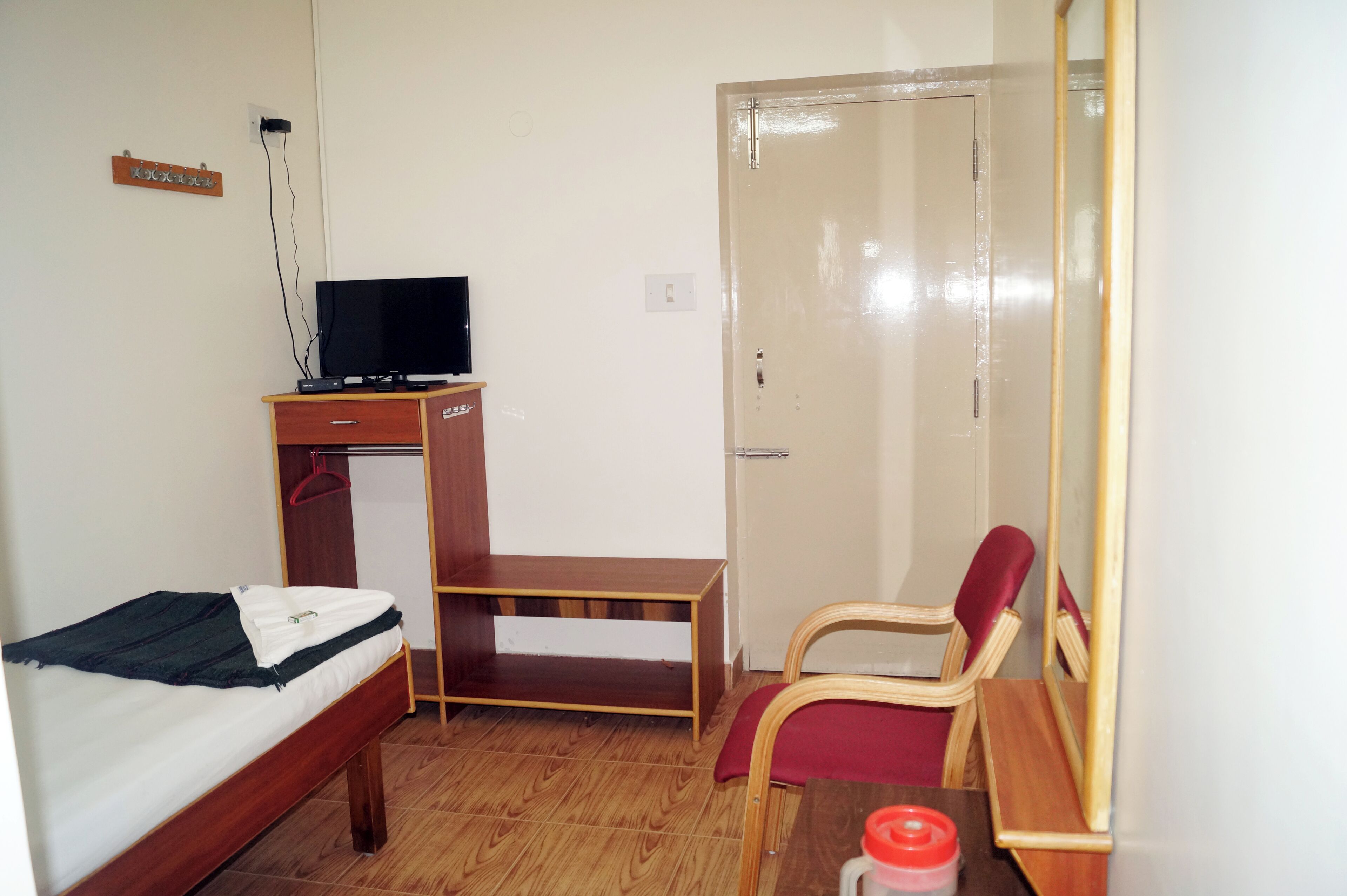 A small, clean room with a bed, a desk, a chair, a television, and a wardrobe.