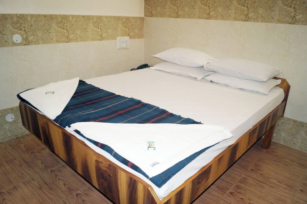 A wooden bed with white bedding and a striped blanket.