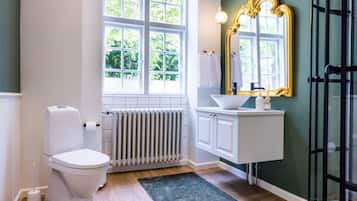 Un baño con inodoro, radiador, lavamanos y un espejo grande.