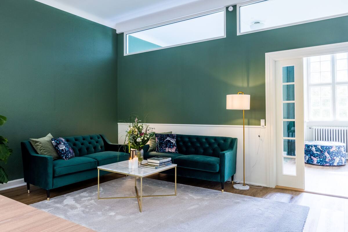 A living room with a teal sofa, a coffee table, and a lamp.