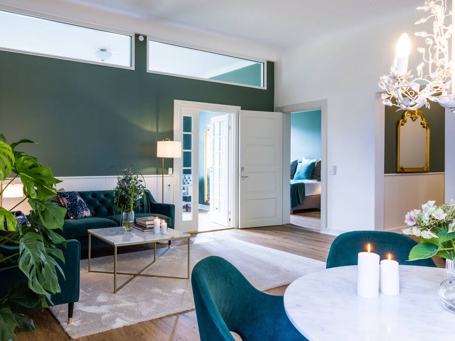 A modern living room with a sofa, a coffee table, and a dining area with chairs and candles.