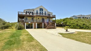 A two-story building with a balcony, a staircase, and a small garden area. - 4668- 85 Ocean Blvd, Walk to Beach | Private Pool & Game Room (Southern Shores)