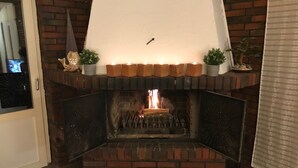A brick fireplace with a white mantel, lit candles, and decorative items.