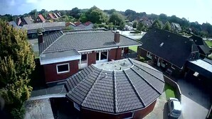 A residential area with houses featuring sloped roofs and a central circular structure with a flat roof.