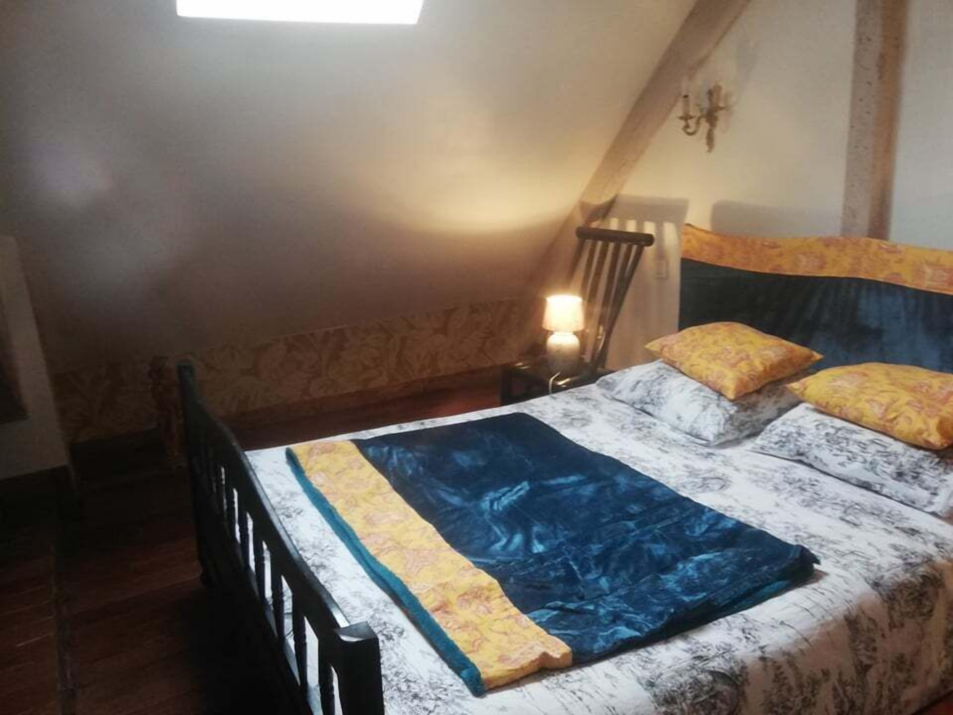 Ein Schlafzimmer mit einem Bett, einem Nachttisch, einem Sessel und einem Fenster.
