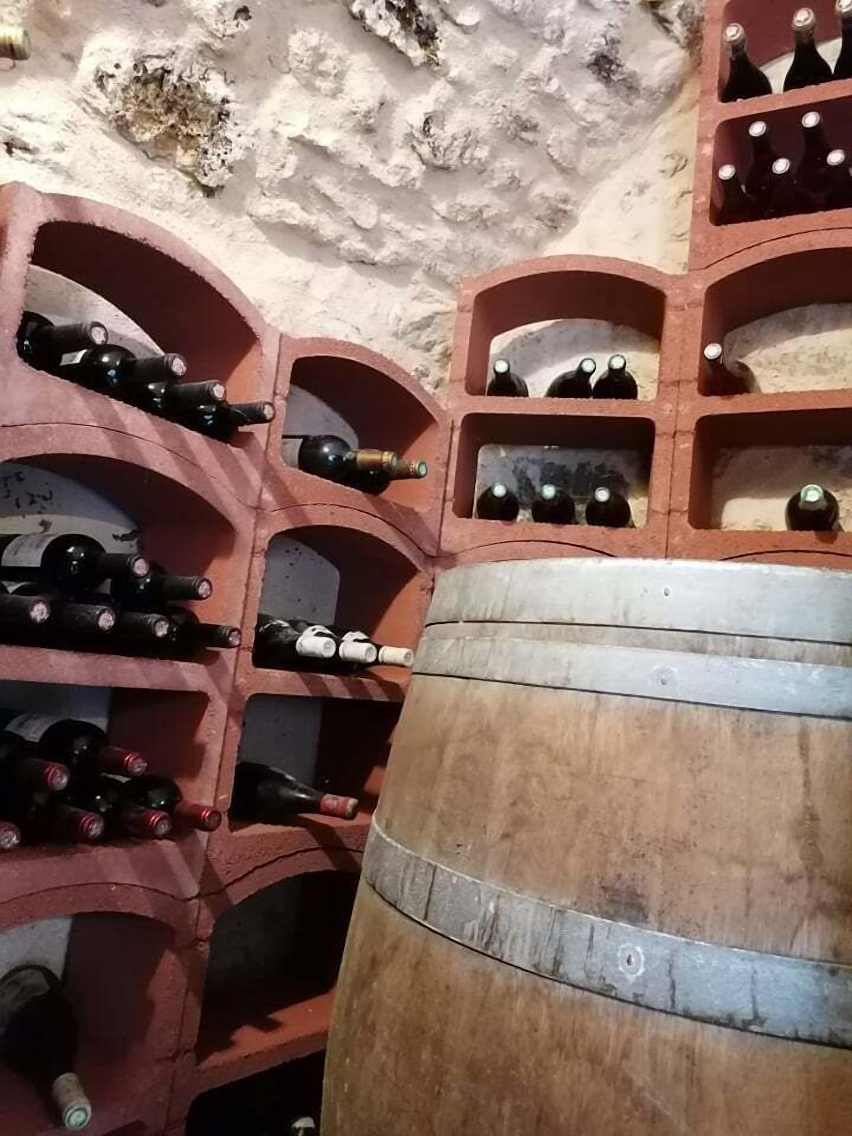 A wine cellar with multiple wooden shelves and a large barrel.