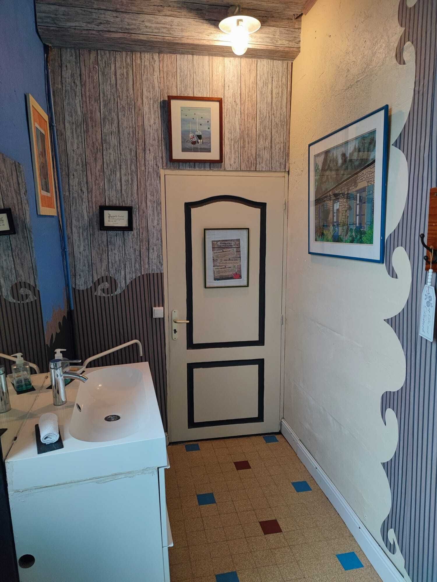A bathroom with a sink, mirror, and framed pictures on the walls.