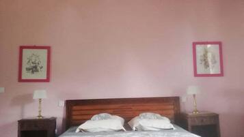 A bedroom with a wooden bed frame, two bedside tables with lamps, and pink walls.