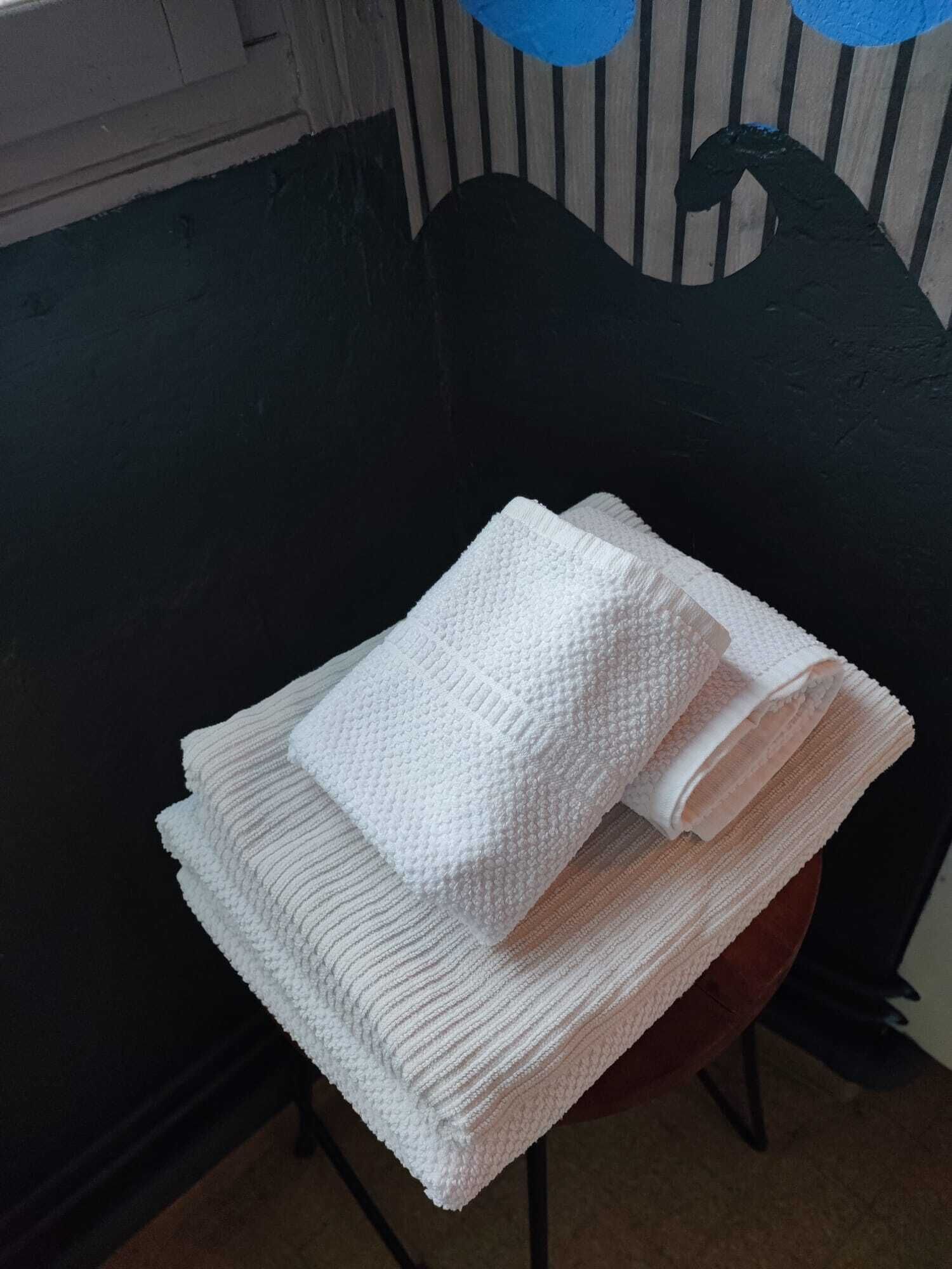 A stack of white towels on a chair with a dark green backrest.