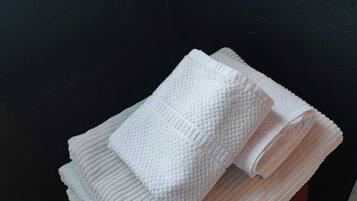 A stack of white towels on a chair with a dark green backrest.