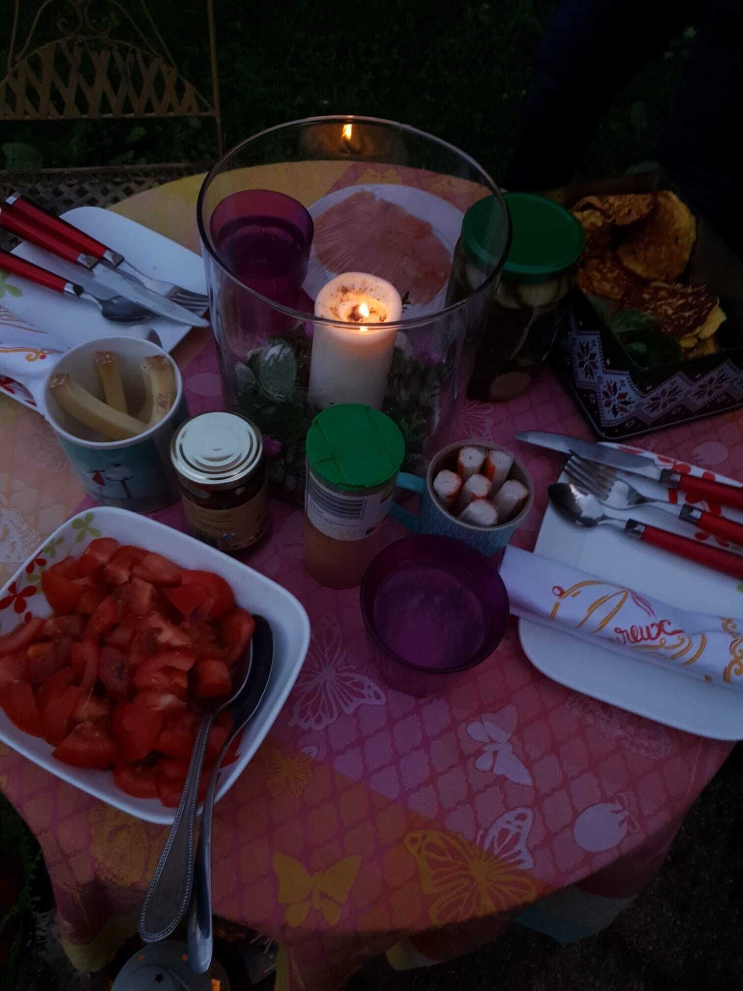 Una mesa con comida, una vela y cubiertos.