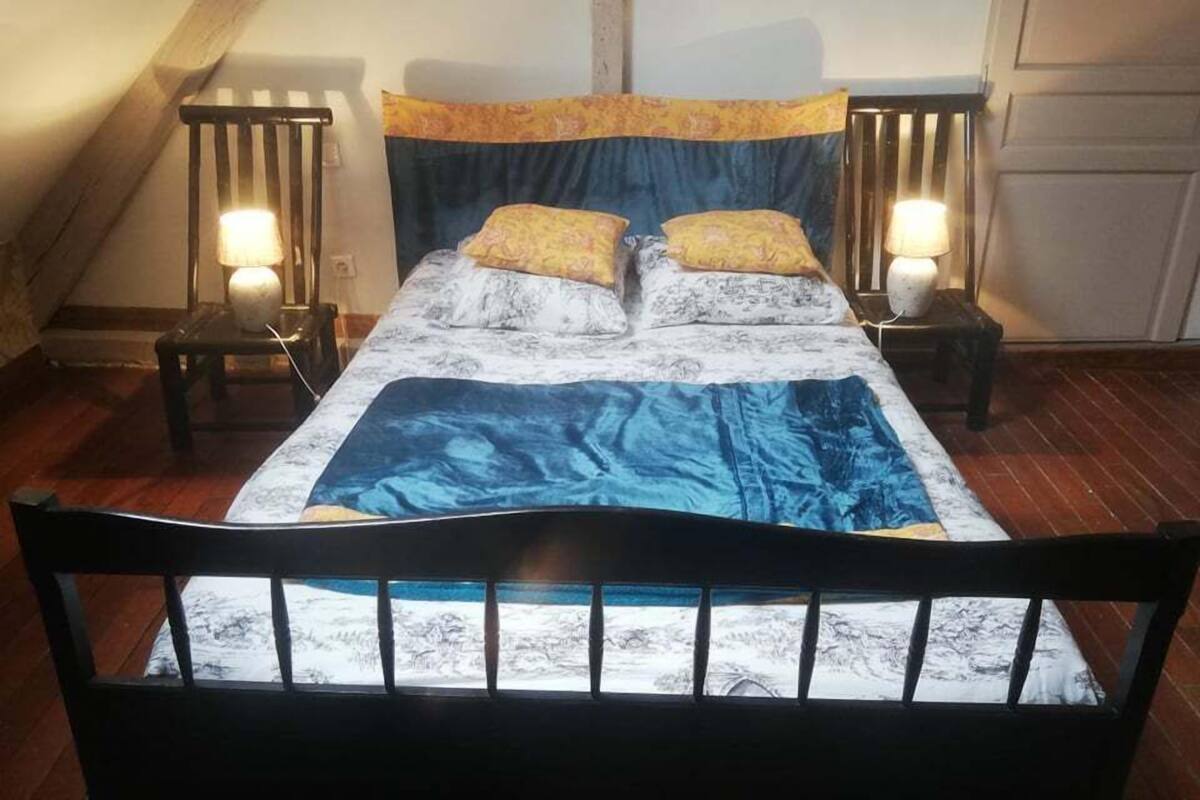 A bedroom with a bed, two bedside lamps, and a wooden headboard.