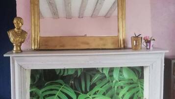 A fireplace with a white mantel, a gold-framed mirror, and a bust sculpture.