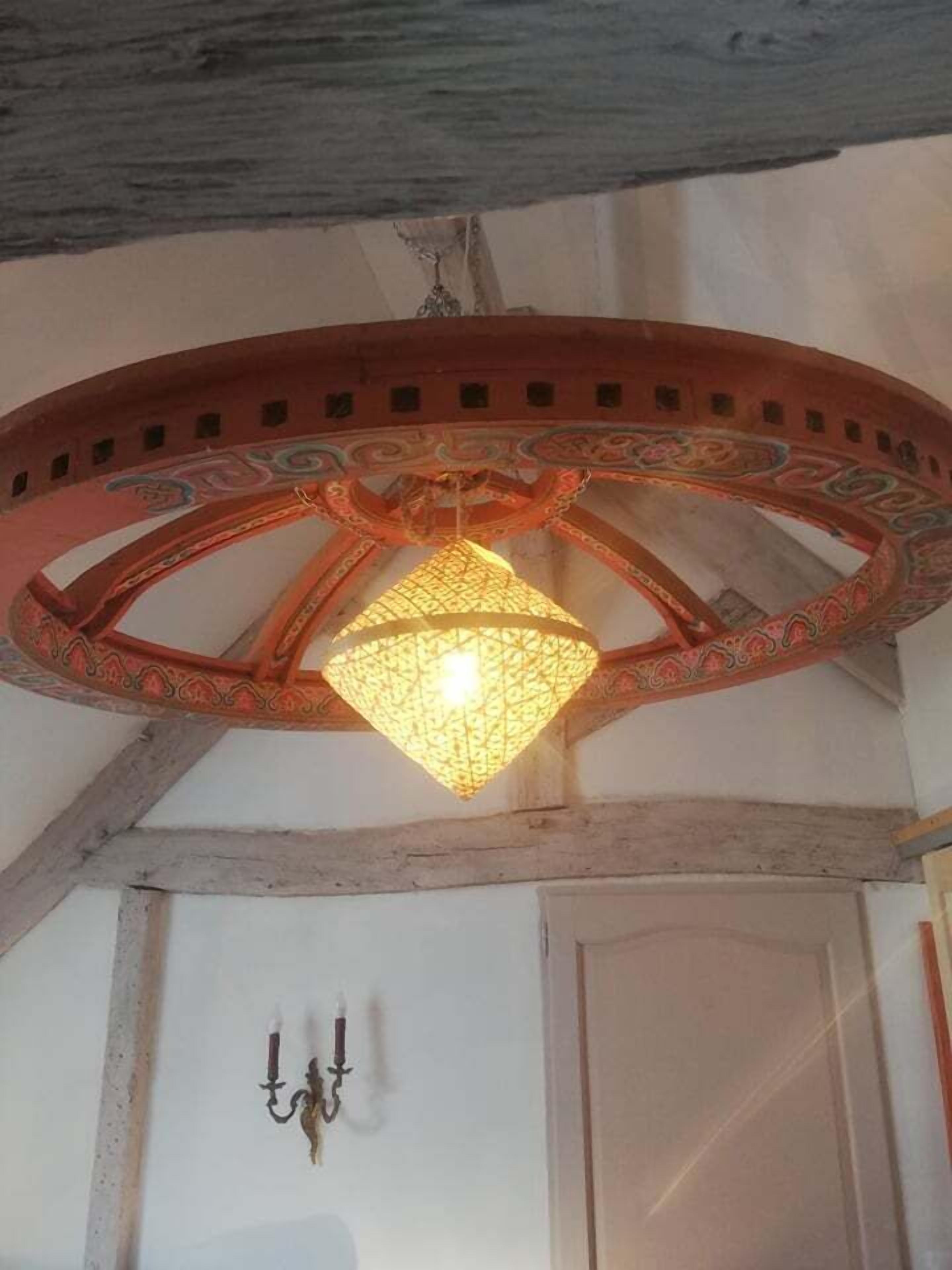 Une pièce dotée d’un plafond en bois, d’un élément décoratif circulaire au centre du plafond et d’un chandelier fixé au mur.