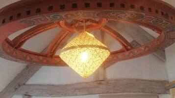 Une pièce dotée d’un plafond en bois, d’un élément décoratif circulaire au centre du plafond et d’un chandelier fixé au mur.